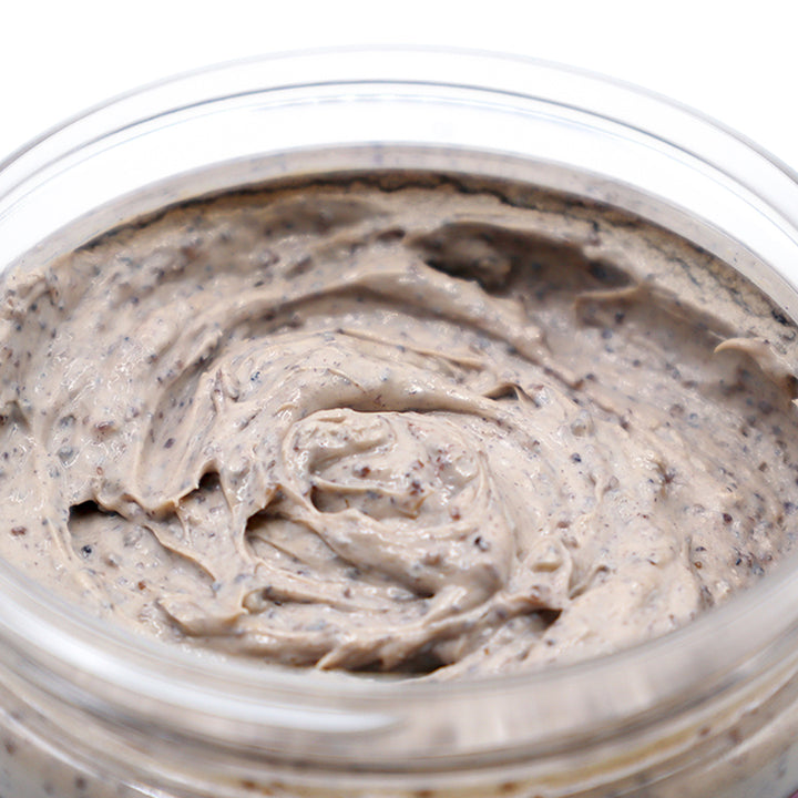 Close-up of a jar filled with a creamy, light brown Lavender & Walnut Soap Scrub