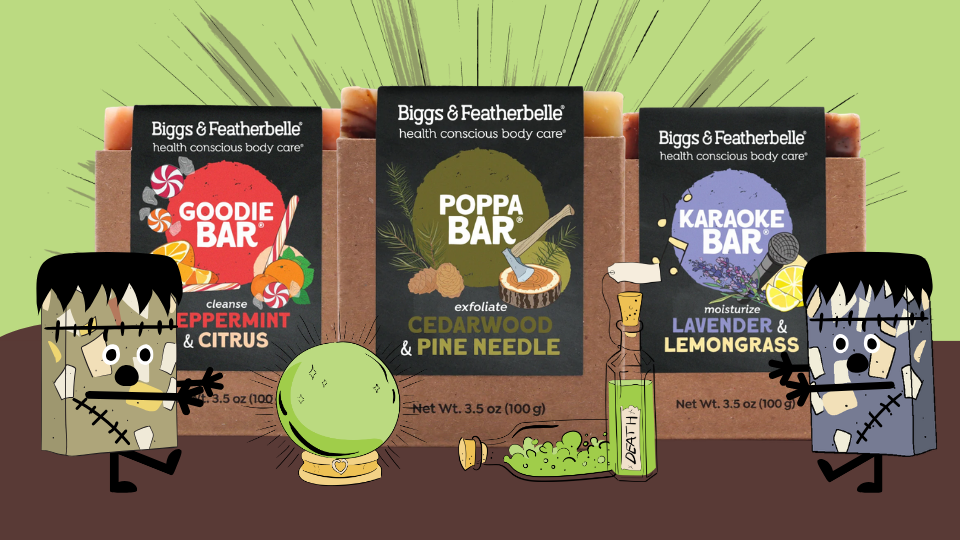 Three Biggs & Featherbelle body care bars arranged on a brown surface with illustrated cartoon Frankenstein and Dr. Nooboo elements.