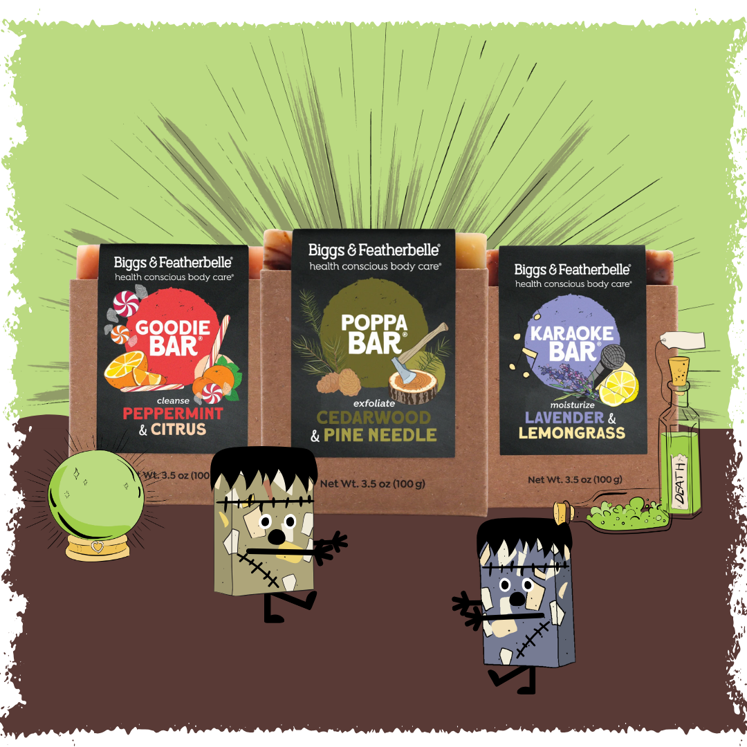 Three Biggs & Featherbelle health conscious body care bars in brown cardboard packaging are displayed against a green and brown illustrated background with cartoon Frankenstein characters and themed props.