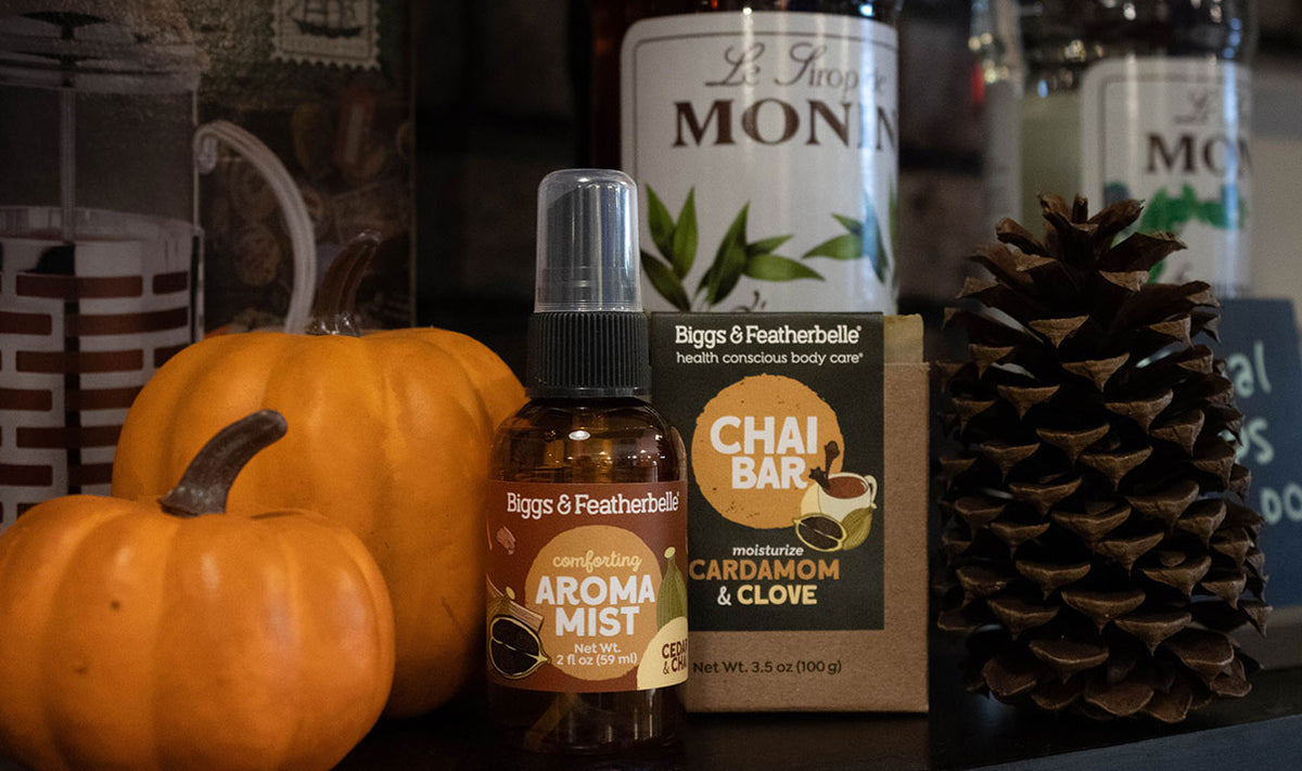 Biggs & Featherbelle handcrafted products and a 'Chai Bar' packaged soap, styled with pumpkins and a pine cone on a dark surface.