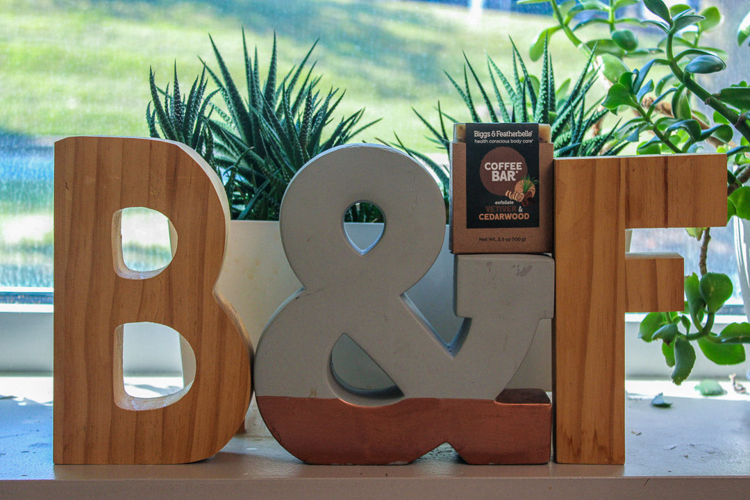 Decorative letters 'B' and 'F' with a Coffee Bar® on top, set against a blurred natural background.